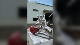 La escultura de bolos de acero inoxidable con espejos captura vívidamente el momento dinámico